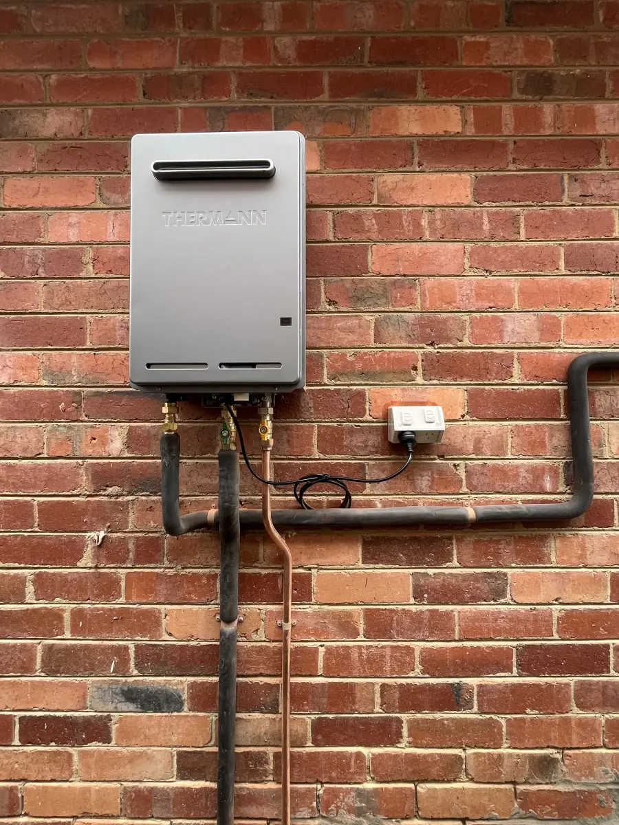 Heat pump hot water unit installed on a brick wall as part of a gas to electric conversion in Melbourne